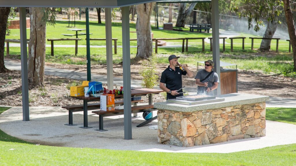Two men cooking on the outdoor barbeques at Hotham Park, Boddington